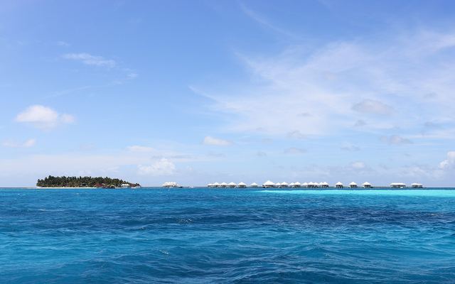Rij watervilla's op palen in een blauwe lagune bij een resorteiland op de Malediven