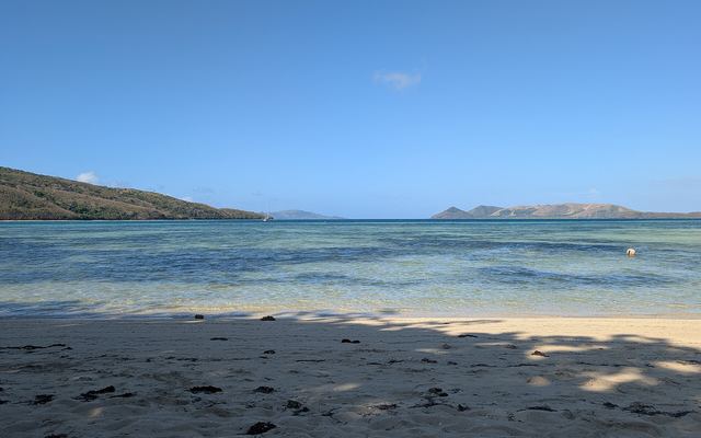 Rustig zandstrand met helder water en eilanden aan de horizon aan de noordkant van Naviti