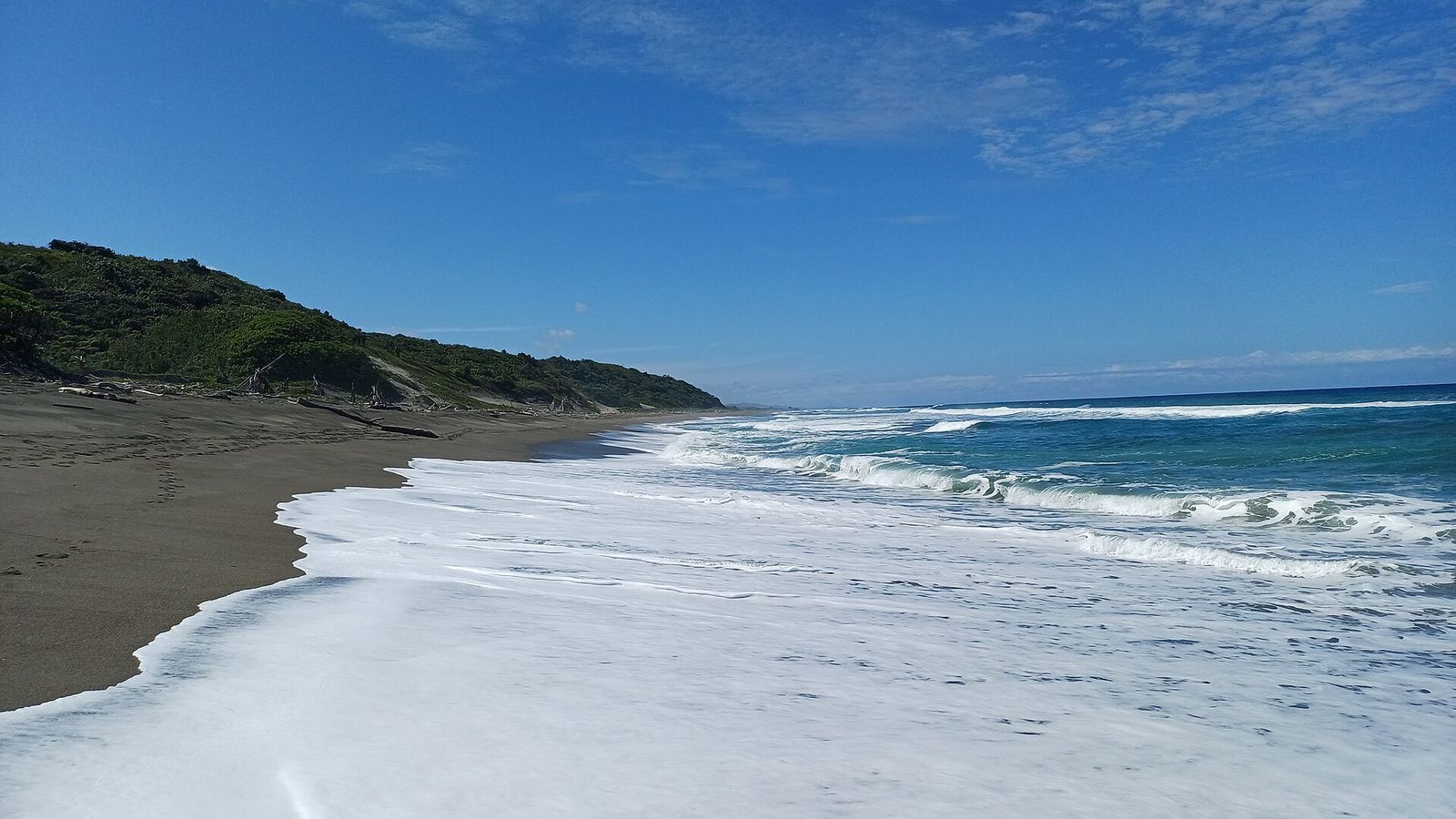 Strand en golven aan de rand van Sigatoka Sand Dunes National Park met begroeide duinen