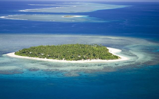 Luchtfoto van Tavarua, een klein eiland met wit strand en een rif eromheen