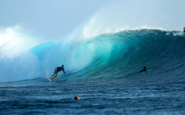 Surfer in de tube van een grote, turquoise golf bij Cloudbreak in Fiji