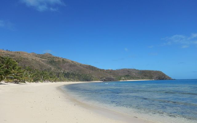 Wit strand met palmen en groene heuvels op Naviti in de Yasawa-eilanden